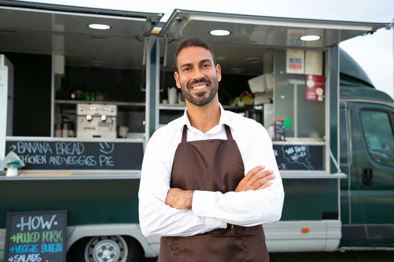 man standing next to a food truck that is open for business
